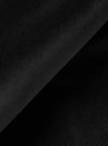 Close-up detail shot of black velvet fabric, showing a diagonal fold across the frame. The matte, fine-pile surface catches subtle light variation, revealing the texture and depth of the material against the darker shadow of the fold beneath.