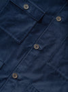Close-up flat lay of the navy velvet Dockside jacket. The soft, short-pile velvet fabric is shown in detail alongside a buttoned chest patch pocket, a centre-front button placket with four-hole grey buttons, and the edges of two lower patch pockets.