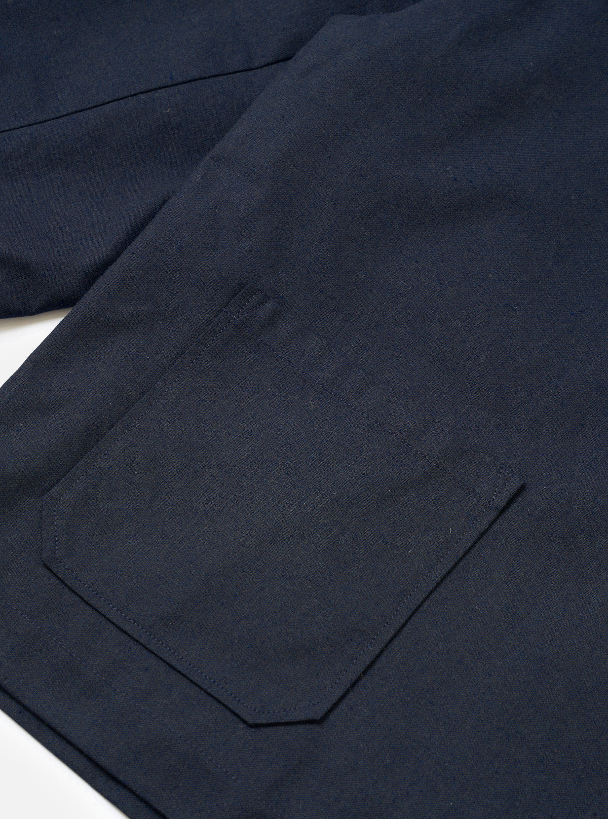 A close-up detailed view of a model wearing the Navy Lucca Suiting Ives Jacket in a studio setting, focusing on the buttoned front placket, collar construction, and texture of the dark navy suiting fabric.