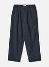 Navy flannel Oxford trousers laid flat on a light grey studio backdrop. The fabric has a fine pinstripe texture in navy. Features an elasticated waistband with a single button closure, a woven brand label, front pleats, slanted side pockets, and turned-up cuffs at the hem. Wide, relaxed leg with a tapered ankle.