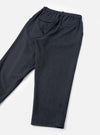 Navy flannel oxford trousers laid flat on a white surface, showing the rear. The elasticated waistband is visible at the top, with two back pockets: one buttoned flap pocket on the left and one button-through welt pocket on the right. The fabric has a fine textured weave. The tapered legs end in turn-up cuffs.