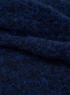 Close-up of the navy blue boucle style fleece fabric of the Lancaster Jacket, showing a looped, textured weave with visible fibre strands in deep blue and dark tones. The fabric is folded to highlight its soft, fluffy surface and dimensional texture.