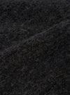 Close-up detail of the charcoal boucle style fleece fabric used on the Lancaster Jacket. The shot shows the dense, curly looped texture of the boucle style weave in dark charcoal grey, with individual fibres visible across the surface. A folded edge runs diagonally across the frame, highlighting the fabric's lofty, textured depth.
