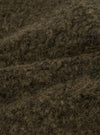 Close-up detail shot of the brown boucle style fleece fabric used in the Lancaster Gilet. The tightly looped, curly texture is clearly visible, with dark brown and warm tan tones running through the fibres. The image shows the fabric folded, highlighting its depth and soft, fluffy surface.