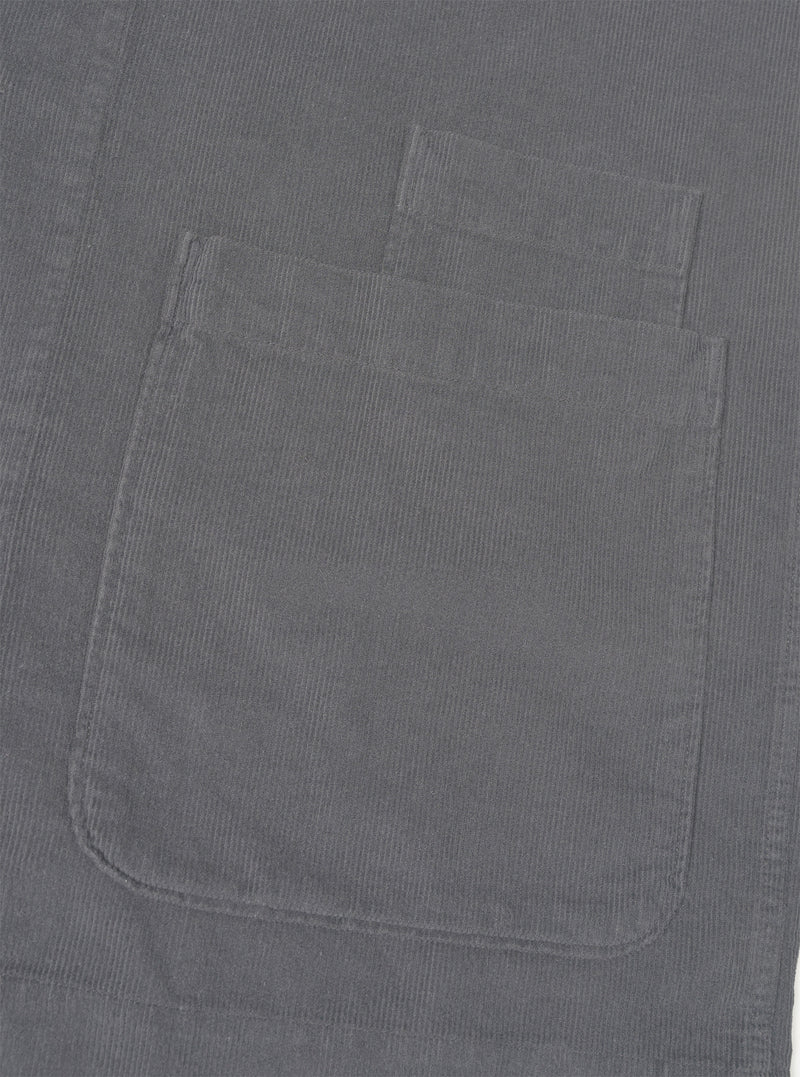 A close-up shot of the Universal Works Grey Fine Cord Bakers Overshirt on a white background, highlighting the fine corduroy fabric texture, collar, chest pocket, and front button details.