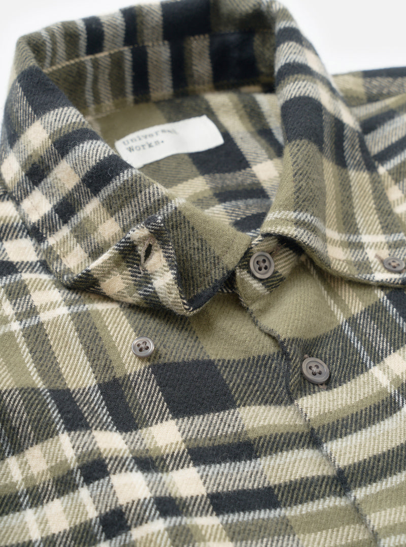 A detailed close-up shot focusing on the cuff and sleeve construction of the Universal Works Olive Jazz Check Standard Shirt, highlighting the organic cotton weave and tonal buttoning detail.