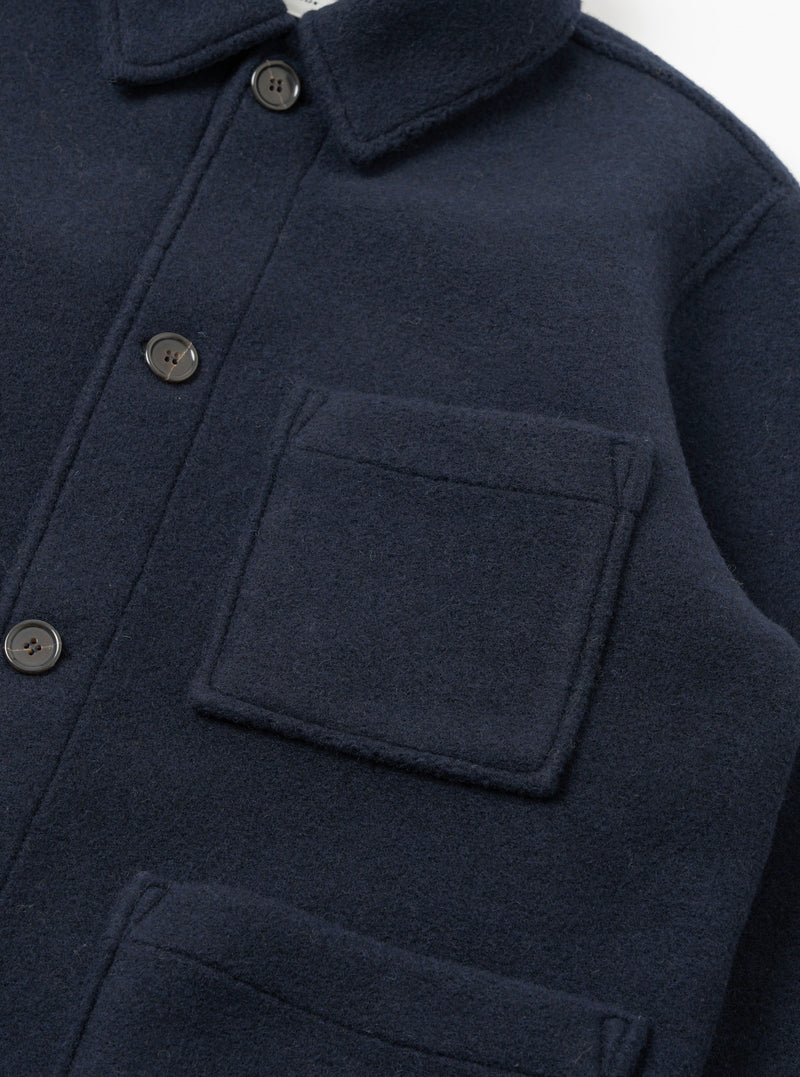 A detailed close-up shot of the Navy Techno Melton Plain Tag Jacket on a white background, featuring the pocket construction, fine stitching, tag detail, and dark navy polyester-wool blend fabric texture.