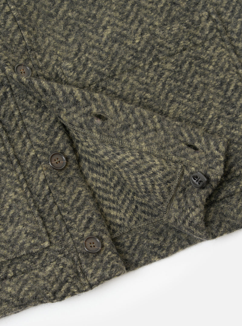 A close-up detail shot of the Olive Raven Fleece Advance Cardigan on a white studio background, focusing on the front buttoning, pocket edging, and tactile surface of the olive green raven fleece fabric.
