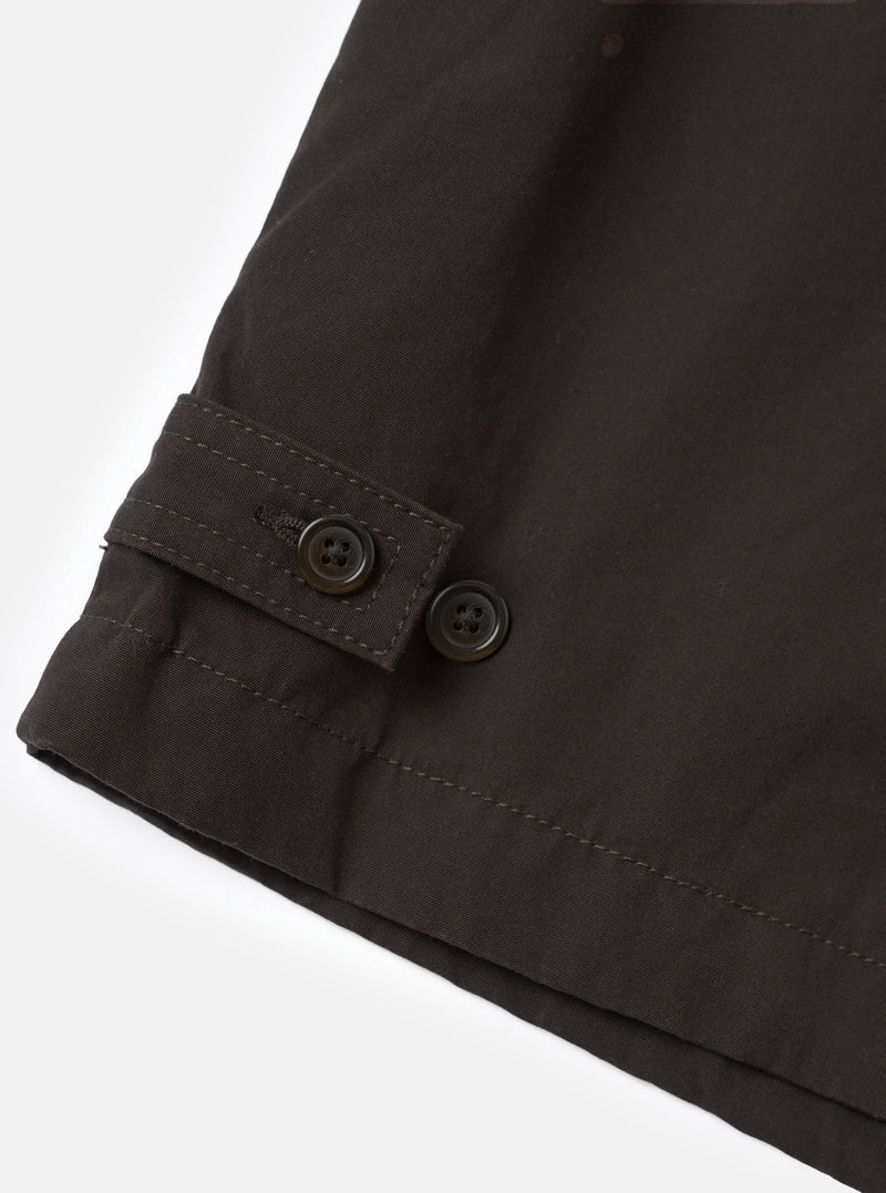 A close-up view of the Brown Micro Canvas Warmus Jacket on a white studio background, focusing on the front button closure, detailed stitching on the chest welt pocket, and smooth brown cotton canvas fabric.
