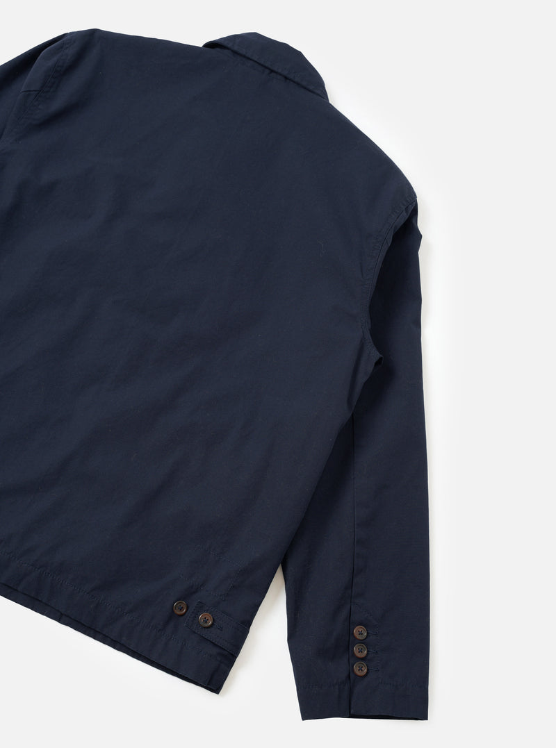 A rear perspective studio photograph of the Navy Micro Canvas Warmus Jacket against a clean white backdrop, showcasing the smooth back construction, shoulder seam stitching, and dark navy cotton canvas material.