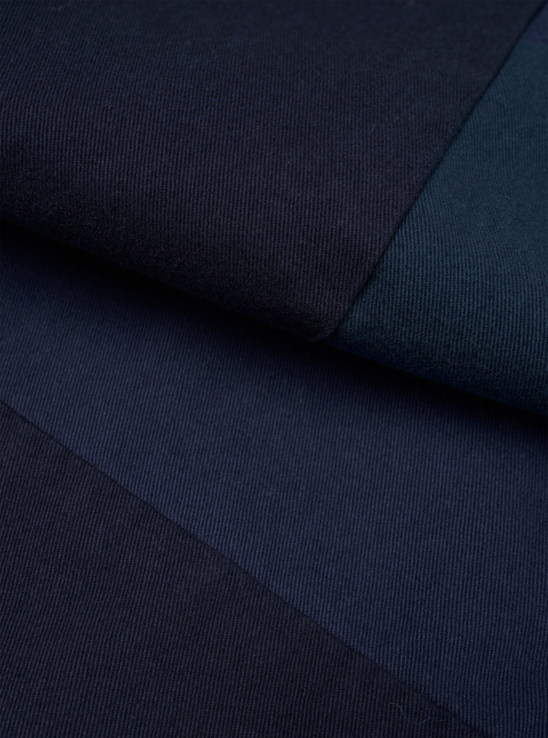 Close-up detail shot of navy twill fabric from the Oxford pant, showing the diagonal weave texture. Two contrasting panels of navy and dark teal twill meet at a sharp seam, highlighting the patchwork construction. No model or mannequin present.