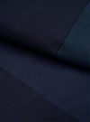 Close-up detail shot of navy twill fabric from the Oxford pant, showing the diagonal weave texture. Two contrasting panels of navy and dark teal twill meet at a sharp seam, highlighting the patchwork construction. No model or mannequin present.