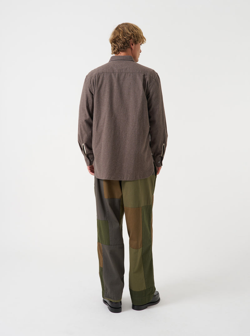 Back view of a model wearing the Olive Patchwork Twill Oxford Pant against a plain backdrop, featuring the relaxed cut, drawstring waistband details, and olive green patchwork fabric structure.