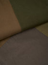 Close-up flat lay showing four colour swatches of twill fabric arranged in diagonal panels: tan, dark olive, muted khaki, and grey-brown. The fine diagonal weave of the twill is clearly visible across all panels, illustrating the fabric options available for the Olive Patchwork Twill Oxford Pant.