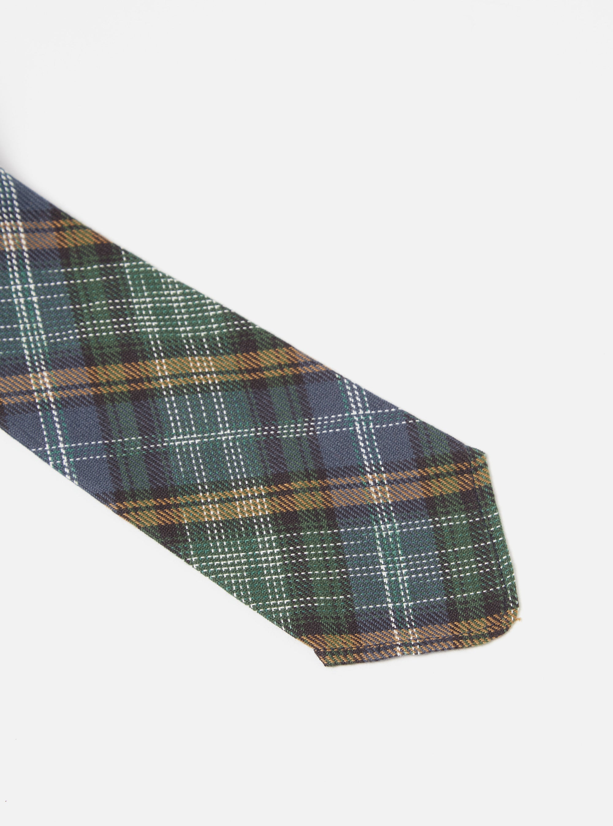 Close-up of the Green Ikat Twill Check Tie on a white background. The tie features a green, blue, and brown plaid pattern with white dotted lines.