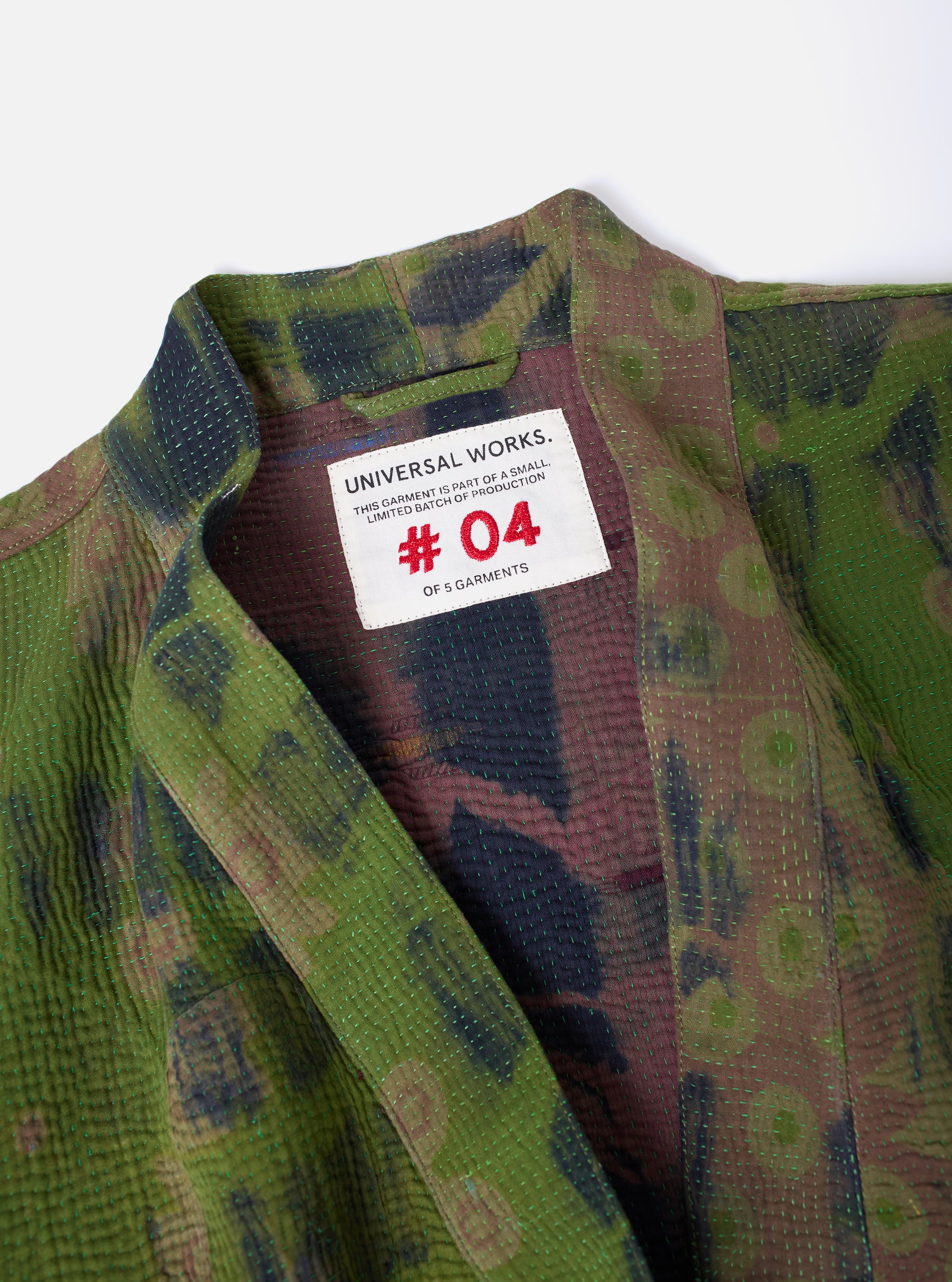 Close-up of the Green Tie Dye #4 Kantha Kyoto Work Jacket - Large, laid flat on a white surface. The jacket features a green and brown tie-dye pattern with visible stitching.