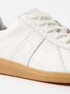 Close-up of the Novesta for Universal Works Off-White/White Leather German Army Trainer. Features white leather upper, white laces, and a gum sole. Shot on a white background.