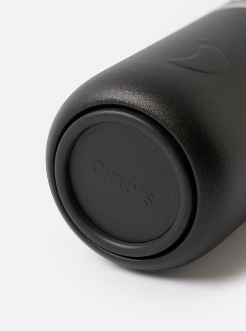 Studio shot of the Chilly's x Universal Works Onyx Series 3 500ml Water Bottle standing upright on a plain white background, highlighting its matte black finish, body, and secure lid.
