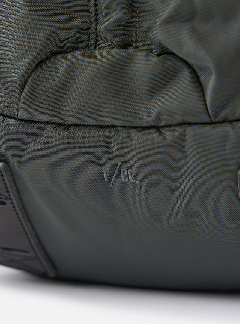 Close-up of the F/CE.® Grey Recycled Nylon 420 re/cor Travel Backpack on a white surface. The brand logo is visible on the grey nylon material.