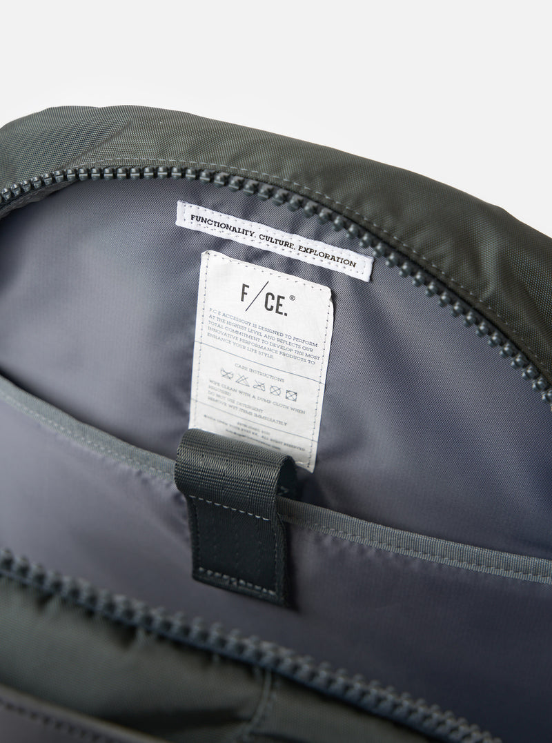 Close-up of the inside of the F/CE.® Grey Recycled Nylon 420 re/cor Travel Backpack. Shows the grey nylon lining, zipper, and care instructions tag. Shot on a white background.