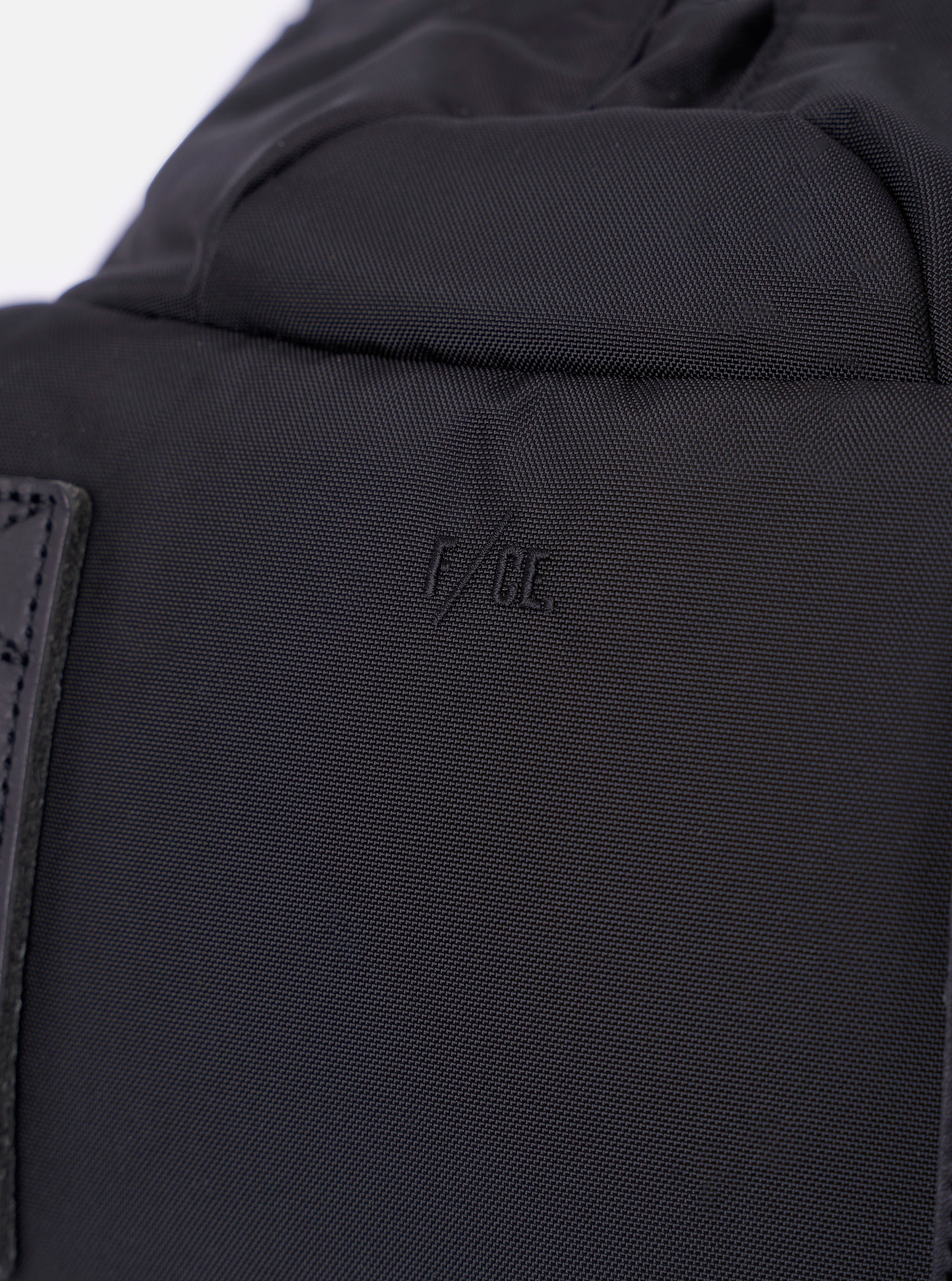 The F/CE. Black Recycled Nylon 420 re/cor Travel Backpack is shown from the back as a flat lay against a plain white background. The image highlights the padded mesh back panel, the ergonomically curved shoulder straps with adjustable webbing, and the top carry handle. The black recycled nylon fabric has a subtle sheen.