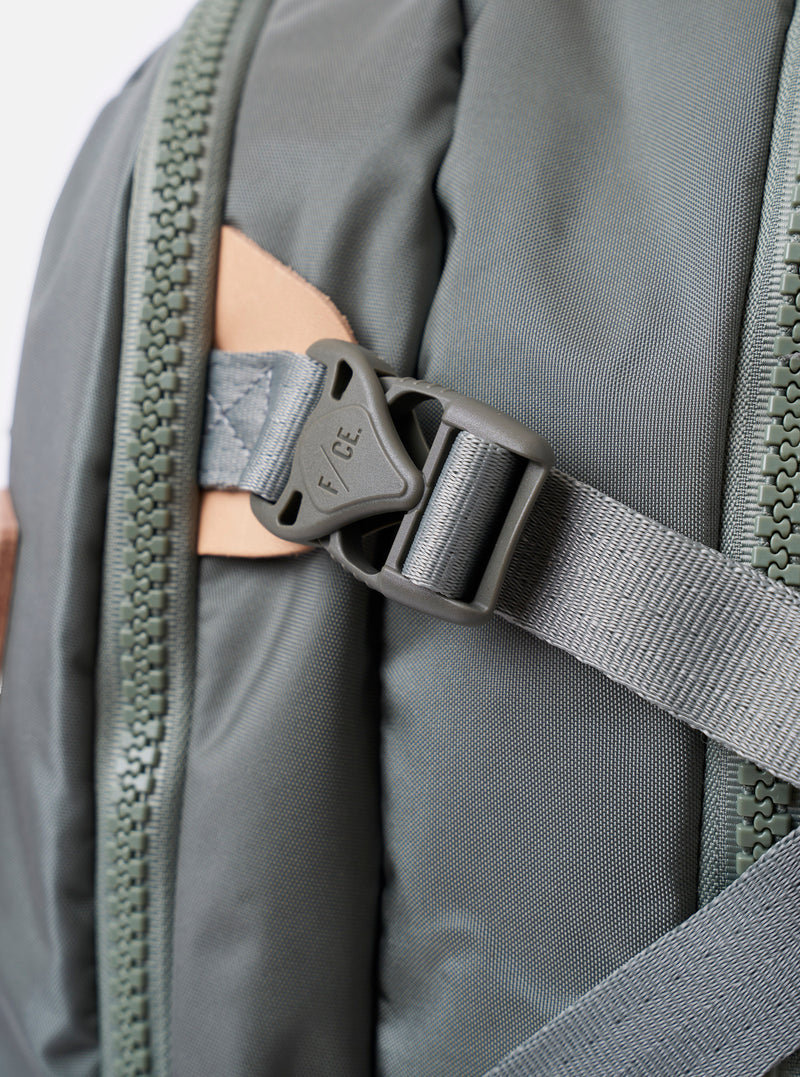 The F/CE.® Foliage Green Recycled Nylon 420 re/cor Travel Backpack is shown from a rear angle against a plain white background. The image highlights the padded back panel made of neoprene and the ergonomic shoulder straps, which feature the MOUNTING T SYSTEM for attachments. The foliage green recycled nylon fabric has a subtle sheen, and
