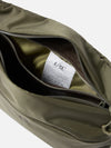 Close-up of the F/CE.® Sage Green 420 re/cor Sacoche, showcasing its sage green material, open zipper, and interior tag. Shot against a white backdrop.