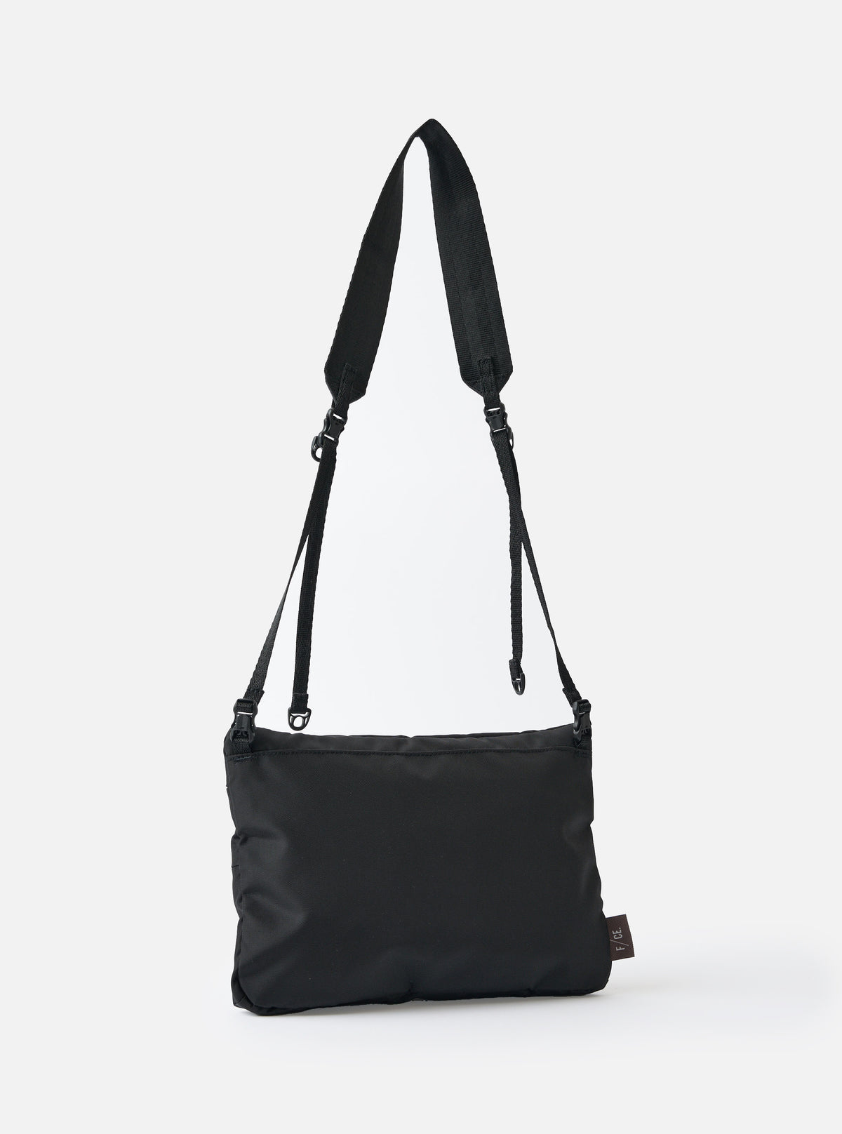 The F/CE.® Black 420 re/cor Sacoche bag hangs against a white backdrop. The black nylon bag features an adjustable strap. The bag has a small branded tag on the bottom corner.
