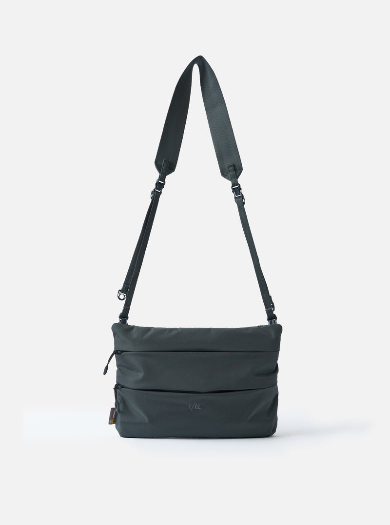 The F/CE.® Grey 420 re/cor Sacoche bag on a white background. The grey bag has a long adjustable strap. The bag is made of a durable material with a subtle texture.