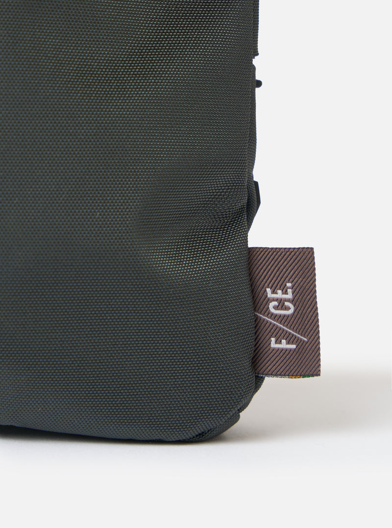 Close-up of the F/CE.® Grey 420 re/cor Sacoche showing the material texture and logo tag on a white background. The sacoche is a dark grey color.
