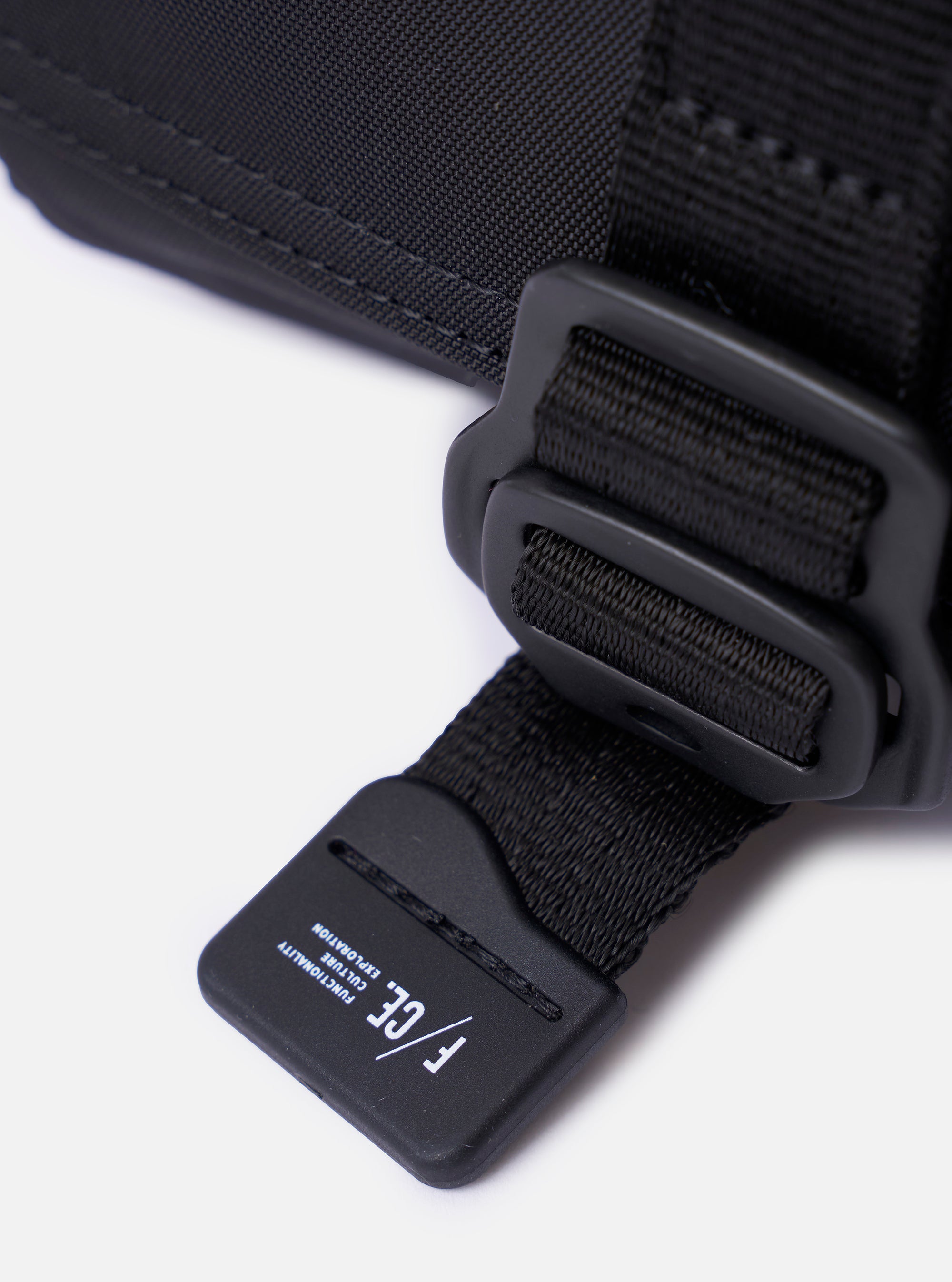 The F/CE.® Black Recycled Nylon 420 re/cor Holiday Sacoche is shown as a flat lay against a plain white background. The compact, rectangular travel bag features two zippered compartments, an adjustable and detachable shoulder strap with plastic buckles, and a small brand label on the front. The black recycled nylon fabric has a smooth, technical appearance.