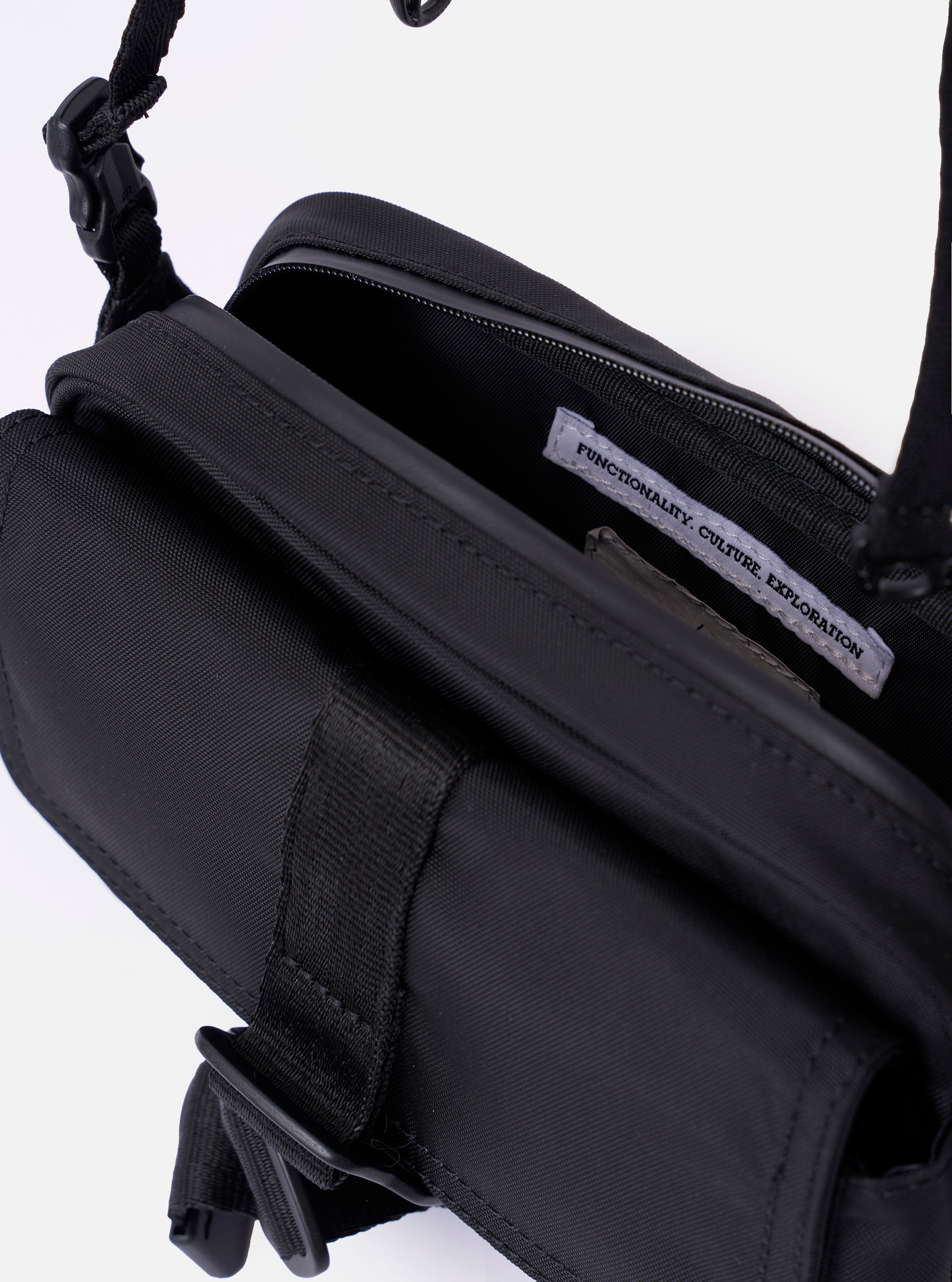 The F/CE. Black Recycled Nylon 420 re/cor Holiday Sacoche is shown from a rear angle against a plain white background. The image highlights the adjustable black shoulder strap attached with plastic buckles and the smooth, high-density weave of the black recycled nylon fabric.