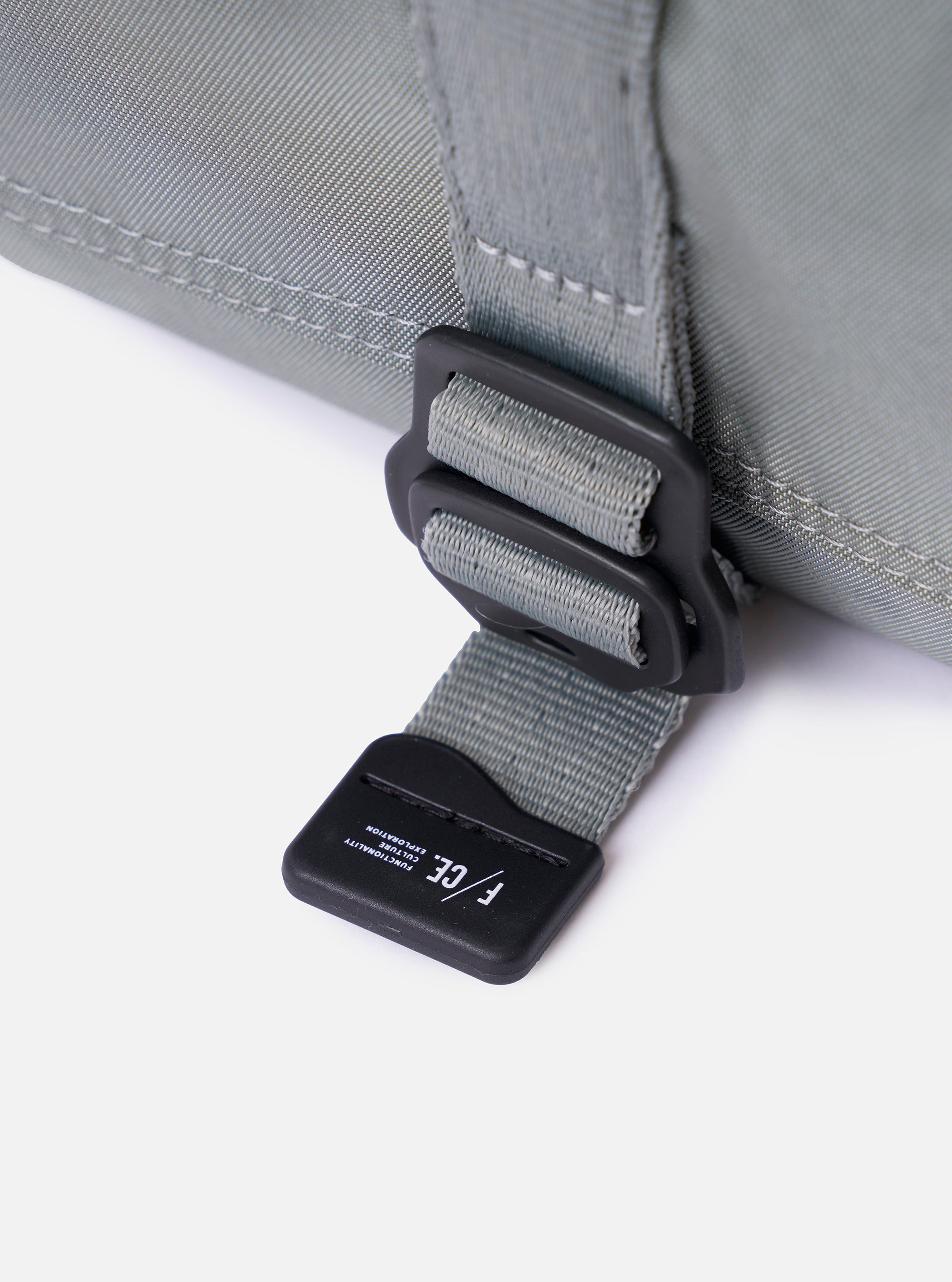 The F/CE.® Foliage Green Recycled Nylon 420 re/cor Holiday Sacoche is shown from a rear angle as a flat lay against a plain white background. The image highlights the adjustable black shoulder strap attached with plastic hardware and a small zippered pocket on the back. The foliage green recycled nylon fabric has a smooth, technical appearance.