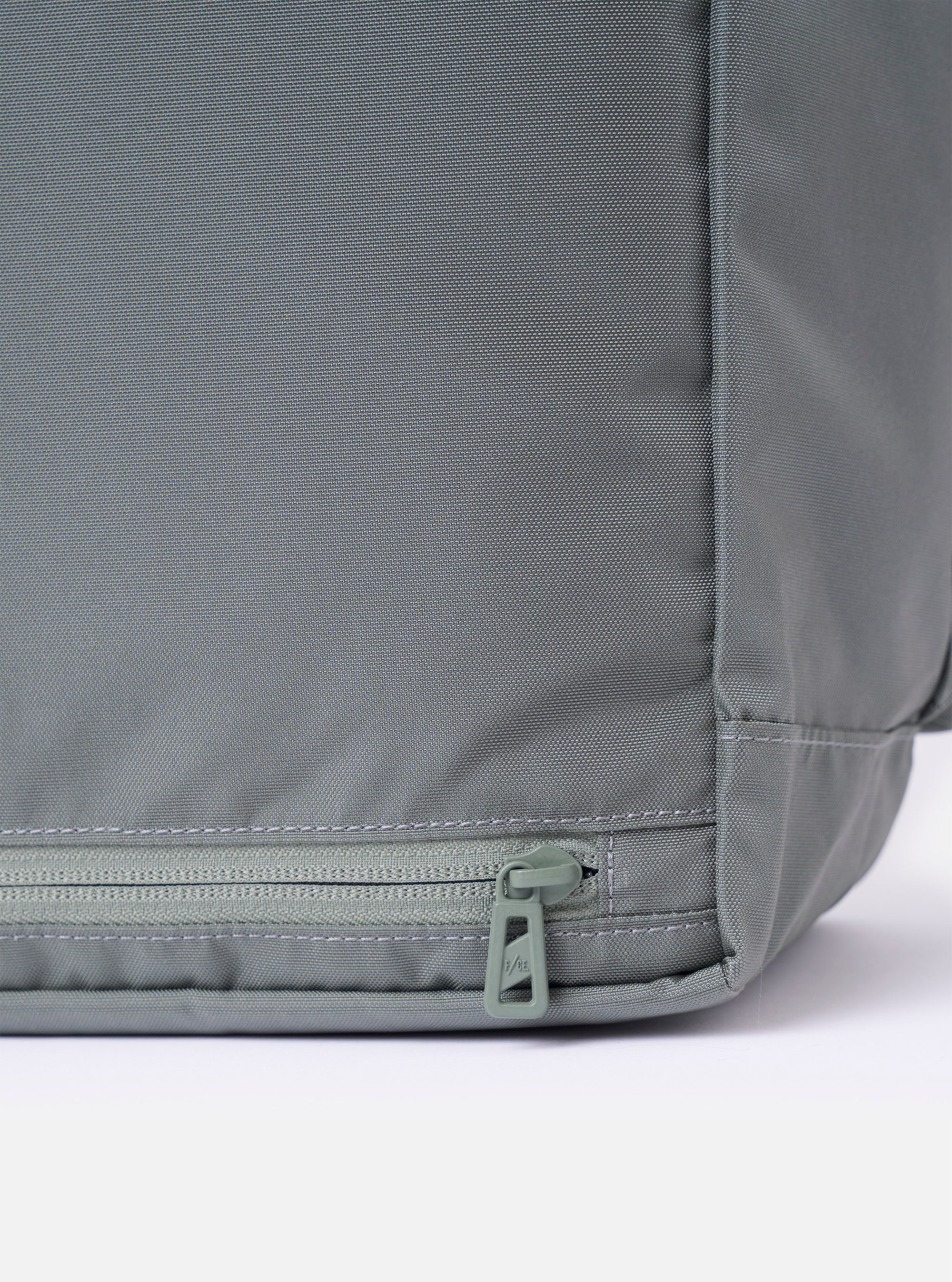 The F/CE.® Foliage Green Recycled Nylon 420 re/cor Courier Shoulder Bag is shown as a flat lay against a plain white background. The image highlights the rear and side profile of the bag, showcasing the durable, textured recycled nylon fabric in a muted foliage green. The wide, adjustable messenger-style shoulder strap and technical webbing details are prominent.