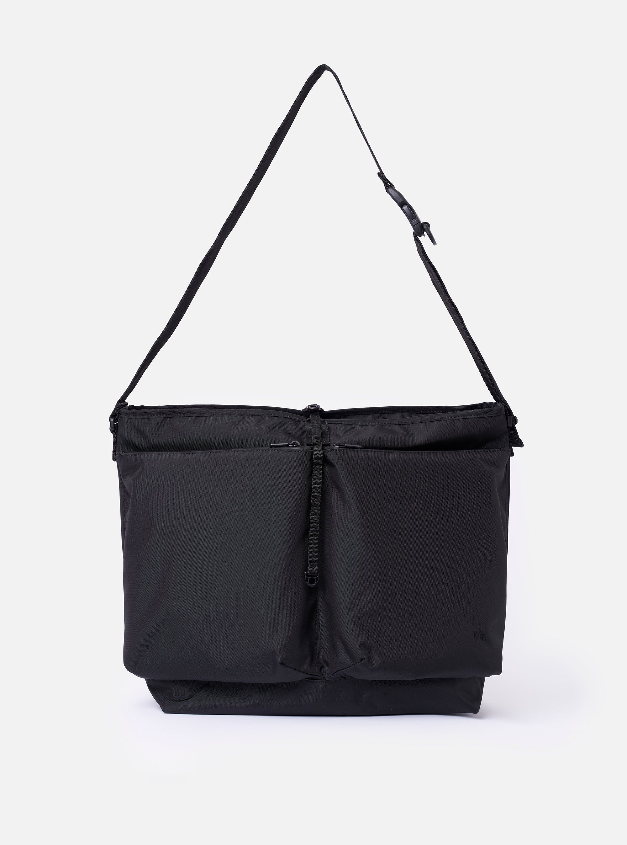 The F/CE. Black Recycled Nylon 420 re/cor Courier Shoulder Bag is shown as a flat lay against a plain white background. The messenger-style bag features a large front compartment with two vertical zips, a main zip closure, and an adjustable shoulder strap with a one-touch buckle mechanism. The black recycled nylon fabric has a subtle twill texture and a slight sheen.