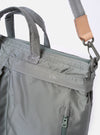 The F/CE. Foliage Green Recycled Nylon 420 re/cor 3-Way Helmet Bag is shown in a detail view as a flat lay against a white background. The image focuses on the top section of the bag, highlighting the sturdy top handles made from seatbelt-grade webbing and the heavy-duty metal zipper closure. The foliage green recycled nylon fabric has a smooth, technical finish.
