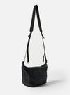 The F/CE.® Black Nylon Cordura Sil Sacoche bag hangs against a white backdrop. The black nylon bag has a thin black strap. The bag is lightweight and durable.
