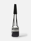 The F/CE.® White Nylon Cordura Sil Portrait bag. Hanging against a white backdrop, it features a black strap, a gray nylon top, and a black grid-patterned bottom.