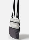 The F/CE.® White Nylon Cordura Sil Portrait bag hangs against a white backdrop. The bag features white nylon and a black grid pattern, with a black strap.