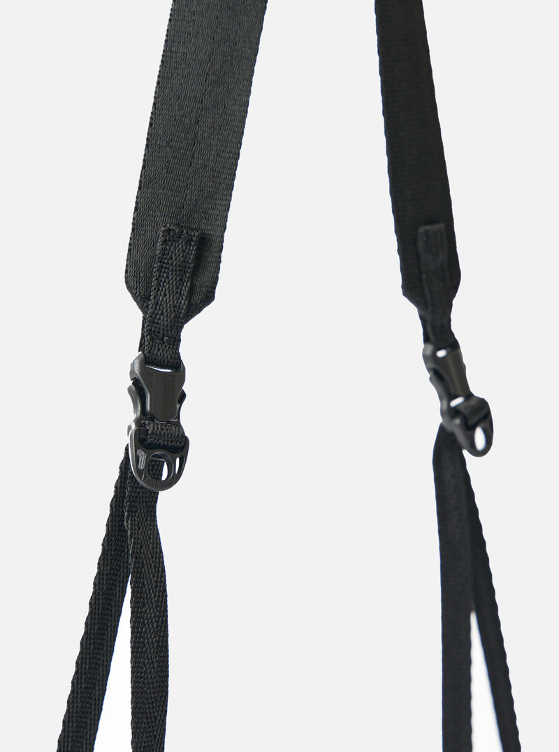 Close-up of the black nylon textured twill drawstring sacoche strap and buckle against a white backdrop. The F/CE.® sacoche is durable and stylish.