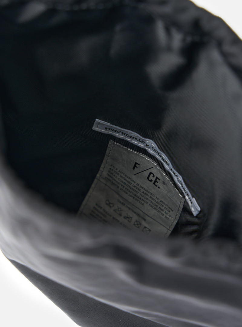 Close-up of the inside of the F/CE.® Black Nylon Textured Twill Drawstring Sacoche, showing the material and brand label on a white background.