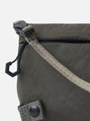 Close-up of the F/CE.® Charcoal Nylon Textured Twill Drawstring Sacoche. Features textured charcoal nylon, drawstring closure, and woven strap. Shot on a white background.