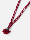 Close-up of the Hanami of Rome Bordeaux/Turquoise Bead Bandana Necklace No.53 on a white surface. Features a braided bordeaux and white fabric with a turquoise bead detail.