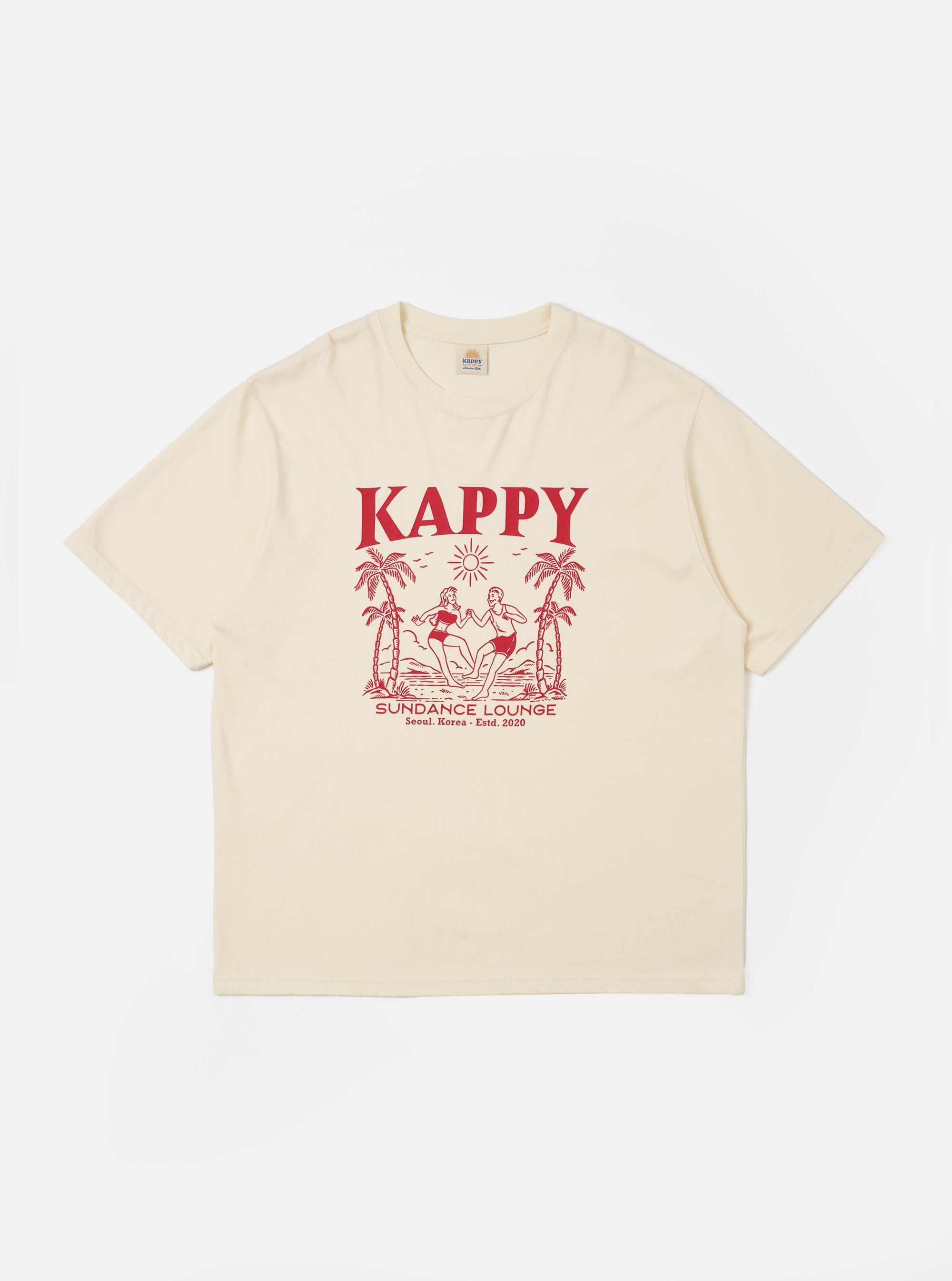 The Kappy Cream Sundance Lounge Half Tee is shown as a flat lay against a white background. The cream-colored t-shirt features a contrasting orange graphic print on the front inspired by holidays. It has a relaxed fit, a simple crew neckline with visible chain stitching, and half-length sleeves.
