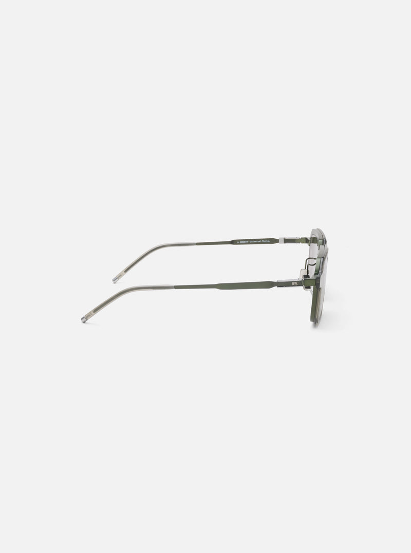 Side view of A. SOCIETY x Universal Works Olive/Green Kowloon Eyewear on a white surface. The frames are olive green with silver accents. 