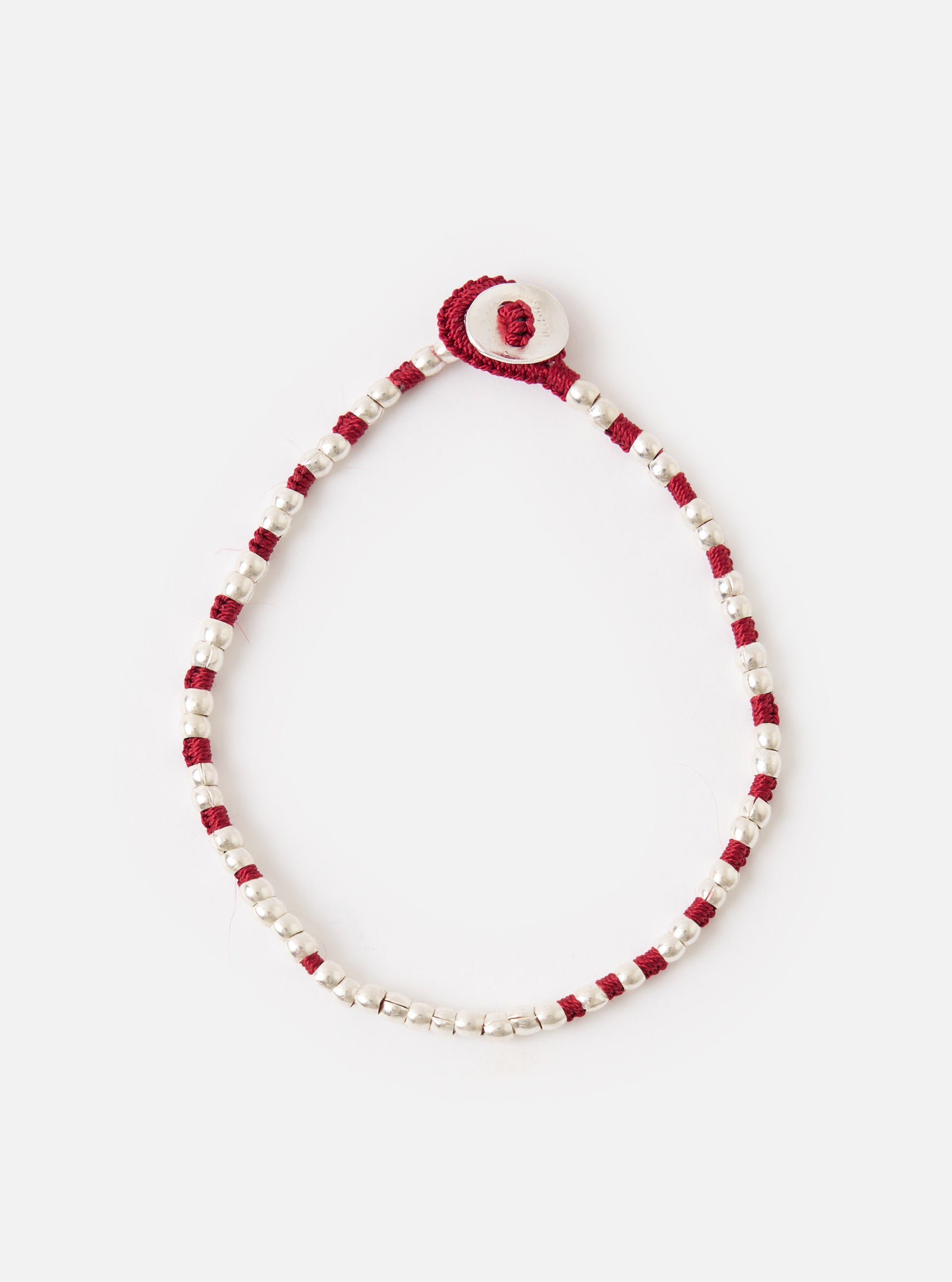 The Mikia Garnet Silver Beads Bracelet on a white surface. The bracelet features silver beads and garnet-colored string, with a silver button closure.