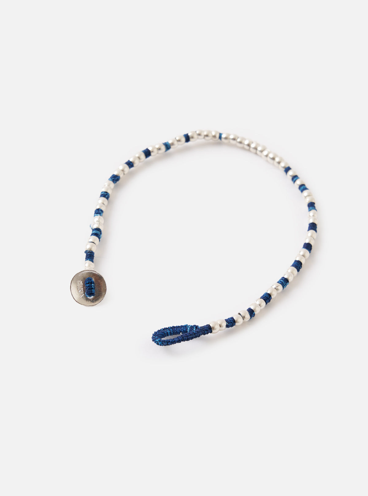 The Mikia Indigo Silver Beads Bracelet on a white surface. The bracelet features indigo thread and silver beads. It has a button closure.