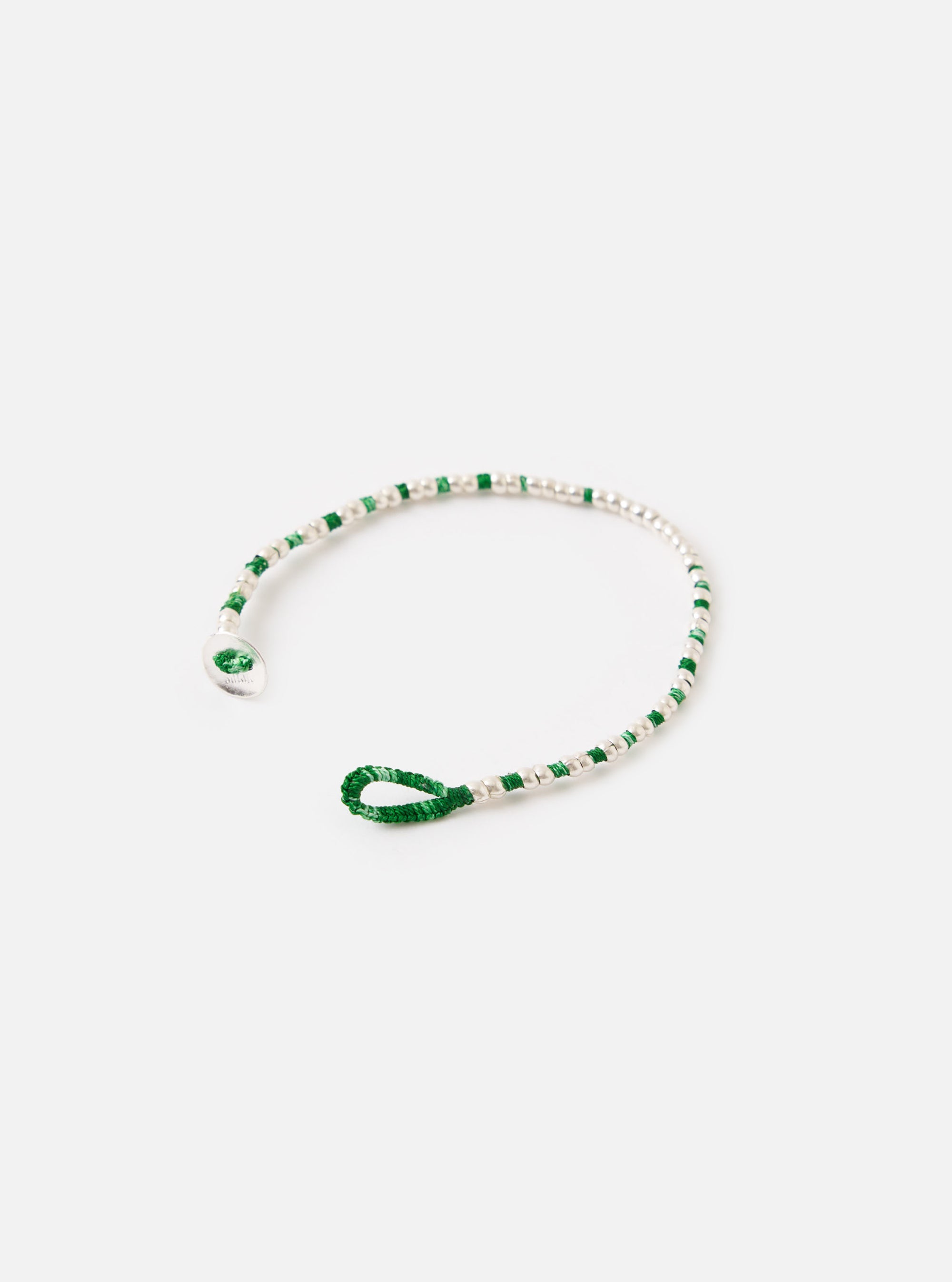 The Mikia Malachite Silver Beads Bracelet on a white surface. The bracelet features green and silver beads. The bracelet is unclasped.