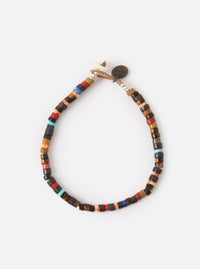 The Mikia Brown Multi Heishi Beads Bracelet on a white surface. The bracelet features brown, red, and blue beads. The bracelet is adjustable.