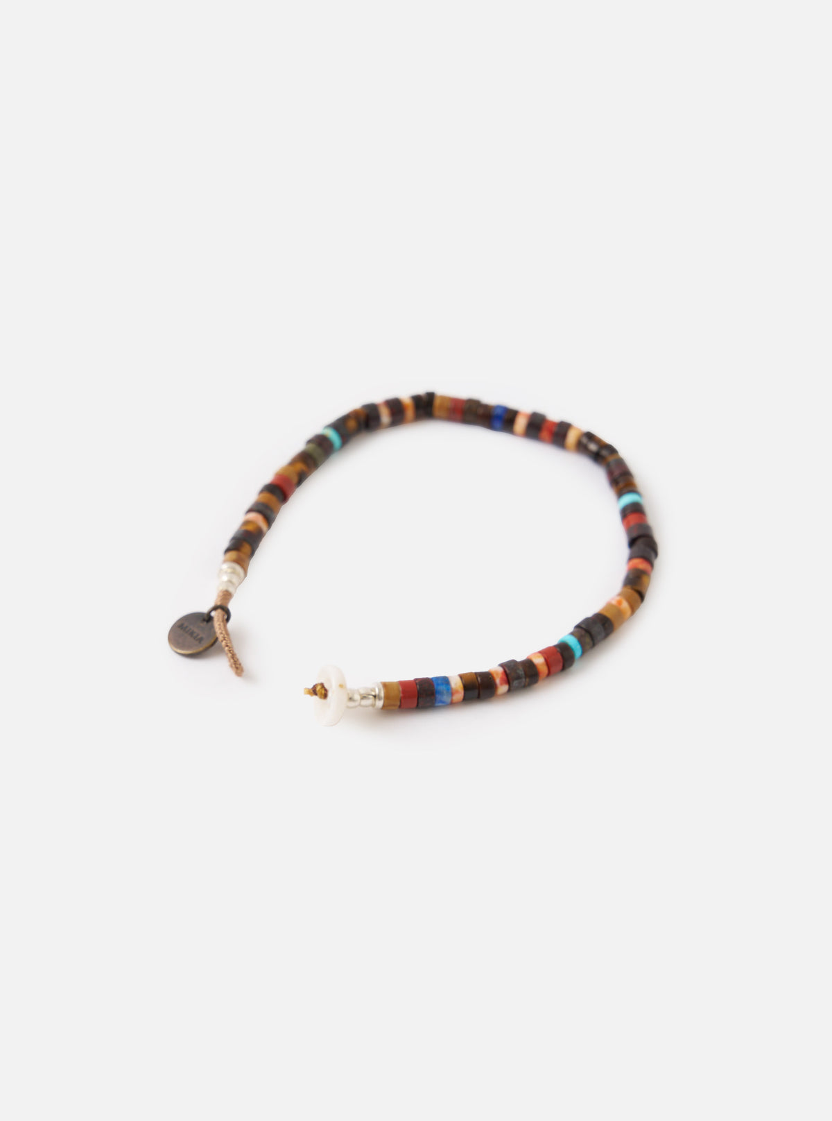 The Mikia Brown Multi Heishi Beads Bracelet on a white background. The bracelet features brown, red, and blue heishi beads strung together with a tan cord and a white button closure.